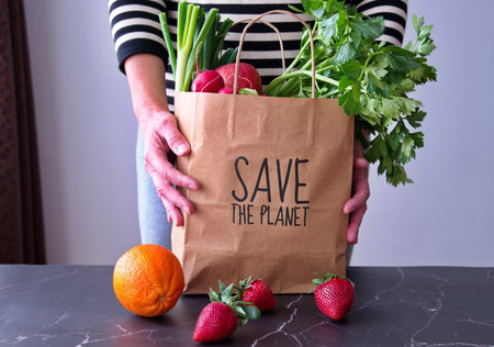 Midsection of senior woman holding paper bag with fruit and vegetables after shoppingの写真素材