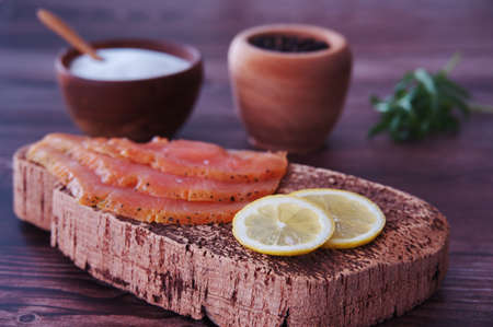 Smoked salmon fillets with lemon, salt and pepper on cutting boardの写真素材