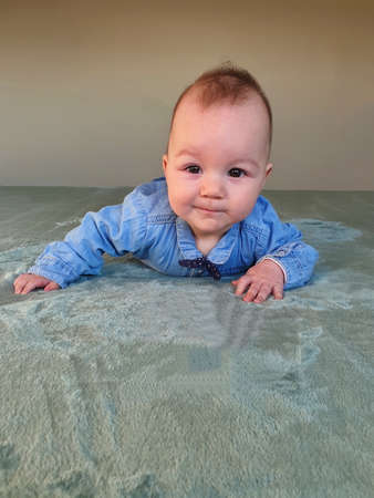 Newborn baby in jeans and bow tie relaxing on bed