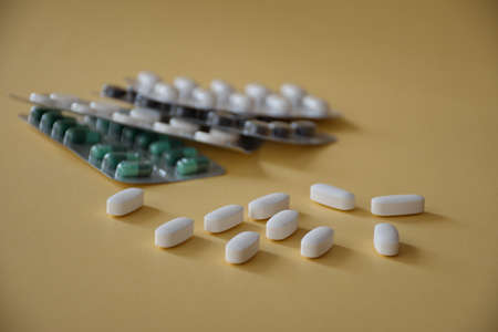 Various capsules and pills on beige background