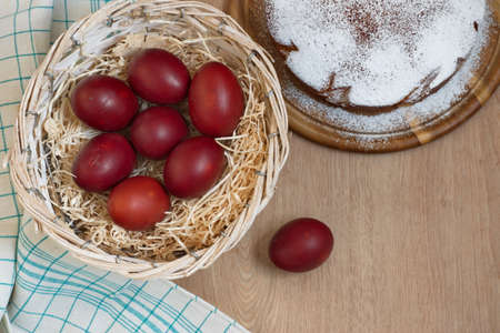 Directly above shot of Easter eggs in basket with straw and cake on wooden backgroundの写真素材
