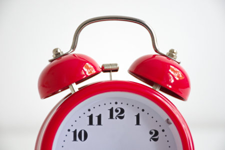 Red vintage alarm clock against the white background