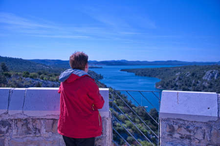Senior woman standing and looking at scenic Mediterranean bayの写真素材