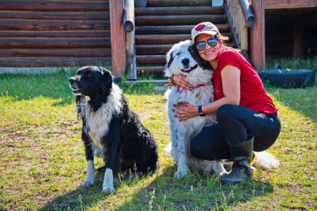 Mature woman hugging a dog in front of her cottageの写真素材