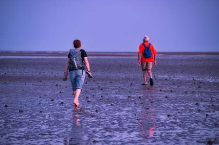 Senior couple walking across the mudflats at low tide