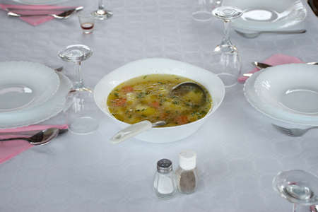 Table with white tablecloth preparing for dinner - soup in a white bowlの写真素材