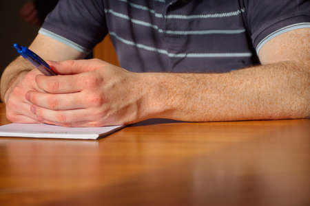 Closeup of the man's hand with freckles. Young man holding pen and making notesの写真素材