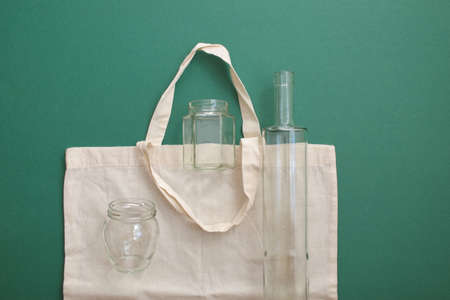 Reusable shopping bag and reusable glass bottles against the green backgroundの写真素材