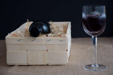 Bottle of wine in wooden box with straw - crystal wine glass with red wineの写真素材