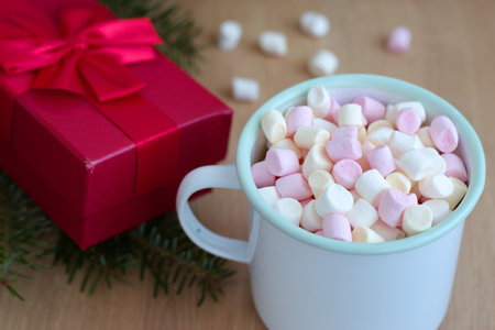 Container with marshmallows and red gift box on the wooden table - Christmas holidaysの写真素材