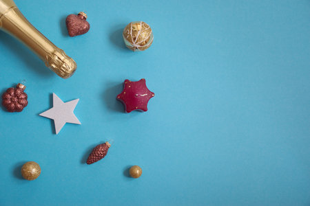 Flat lay of bottle of champagne against the blue background with glitter Christmas ornamentsの写真素材