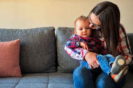 Cute little boy sitting in his mother lap on a sofa