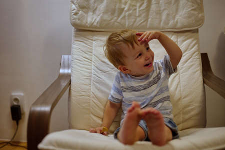 Portrait of cute little boy sitting in armchair