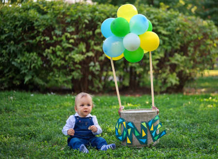 Baby sitting near the basket with balloons celebrating his first birthdayの写真素材
