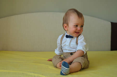 Cute little baby sitting on the bed wearing shirt with bowtieの写真素材