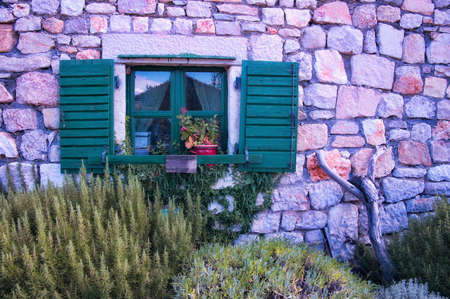 Traditional Mediterranean house with open wooden window and stone wallの写真素材