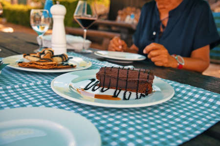 Midsection of woman sitting at the table with cake and pancakes on itの写真素材