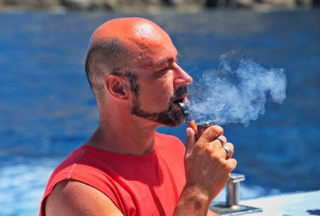 Portrait of a mature man smoking a pipeの写真素材