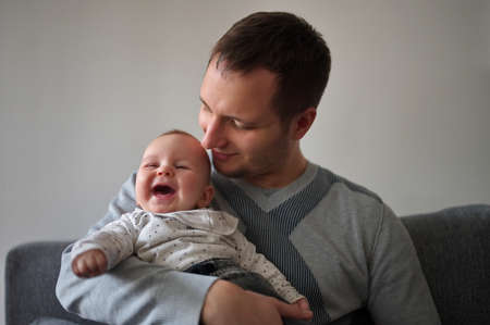 Father sitting on a sofa and holding cute little baby