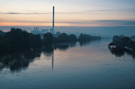 Misty morning on the river with factory chimney reflected in waterの写真素材