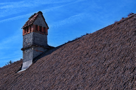 Low angle view of a thatched roof with brick chimneyの写真素材