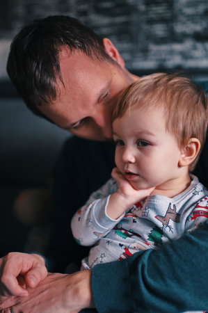 Father sitting on a sofa and holding his cute little boyの写真素材