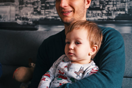 Father sitting on a sofa and holding his cute little boy