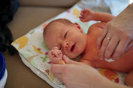 Newborn baby lying on blanket - mother clean her body with cotton wool