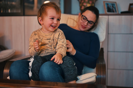 Pregnant mother holding her little toddler in a lap