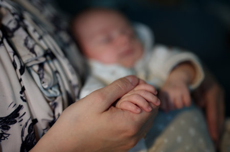 Closeup of newborn baby's hand holding mother's finger