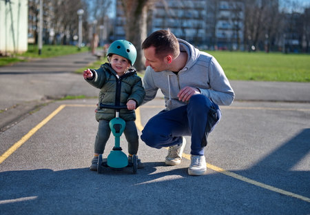 Little toddler on scooter and his father in parkの写真素材
