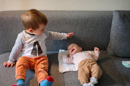 Cute little toddler and his newborn baby sister on the sofa