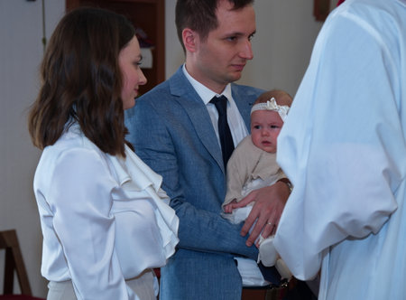 Parents holding their baby girl in a church ready for christeningの写真素材