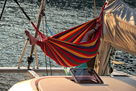 Man relaxing in the hammock set on the sail boat anchored in the seaの写真素材