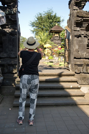 Rear view of tourist taking photo of temple in Bali, Indonesiaの写真素材