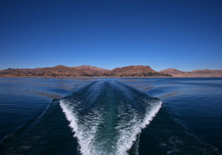 Trail on water surface behind of motor boat on lake Titicaca, Peruの写真素材