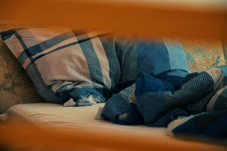 Detail of messy bed sheets through the wooden grid