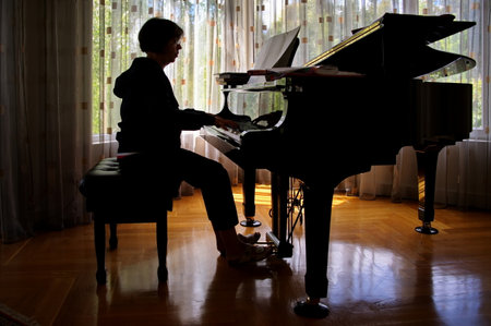 Senior woman playing piano at homeの写真素材