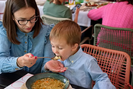 Mother feeding her toddler with the soupの写真素材