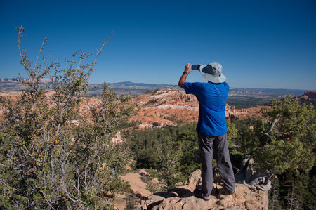 Rear view of senior man taking photo in Bryce Canyonの写真素材