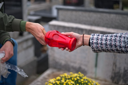 Closeup of hands lighting a candle on a graveの写真素材