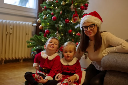Mother and children sitting in front of Christmas treeの写真素材