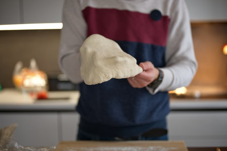 Midsection of man preparing dough for pizza at homeの写真素材