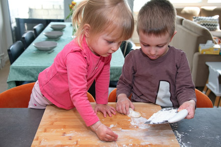 Little children playing with dough and flour in the kitchenの写真素材