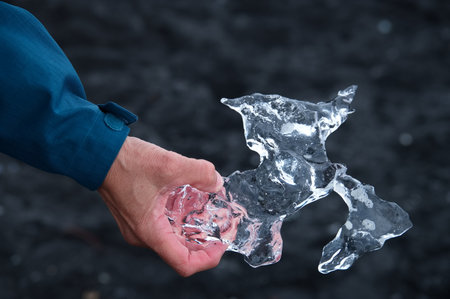 Woman holding piece of ice against lava backgroundの写真素材