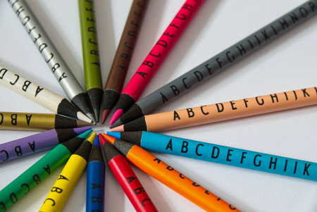 Different colored crayons with letters arranged in a circle on white background. High quality photoの写真素材