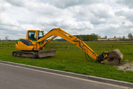yellow mini excavator with a beautiful blue cloudy sky