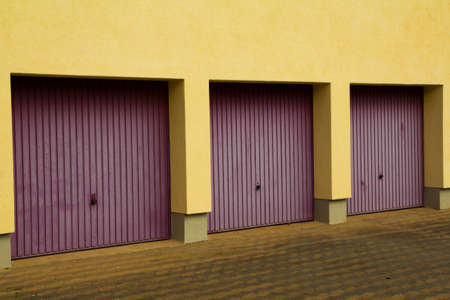 three garage doors processed in a yellow wallの写真素材