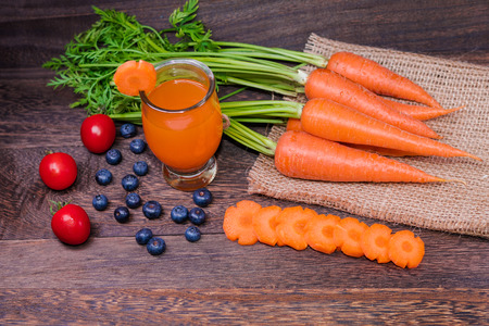 Healthy eating and dieting concept,fresh carrot  and carrot juice or organic healthy juice in glass , tomato ,fruit,vegetables on a grey wooden table wall background with copy space .の写真素材