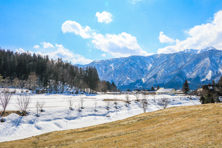 Hakuba mountain range  and  Hakuba village houses  in the winter with snow on the mountain and blue sky and clouds background in Hakuba  Nagano Japan.の写真素材